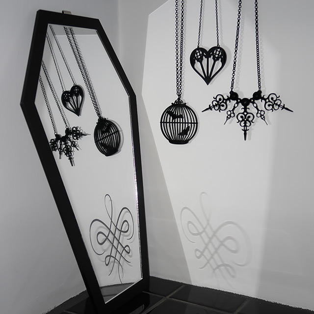 A coffin mirror and three necklaces by Curiology