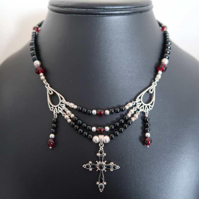 A black onyx and red glass beaded necklace with a black cross pendant