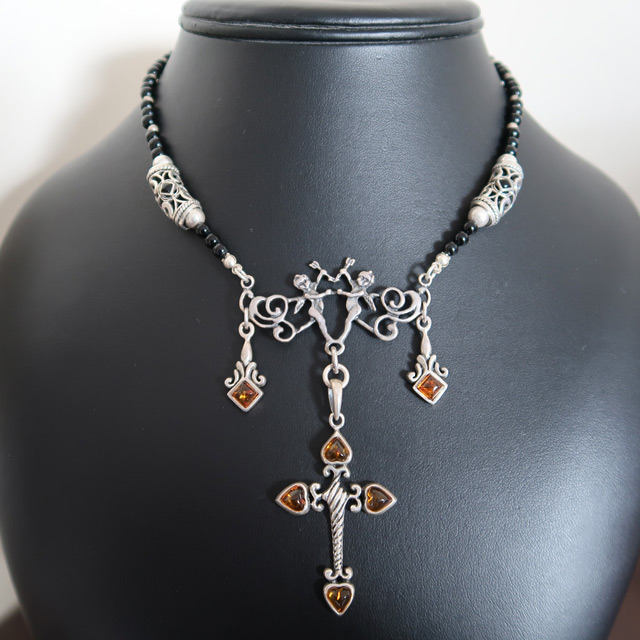 A black onyx beaded necklace with an amber cross pendant