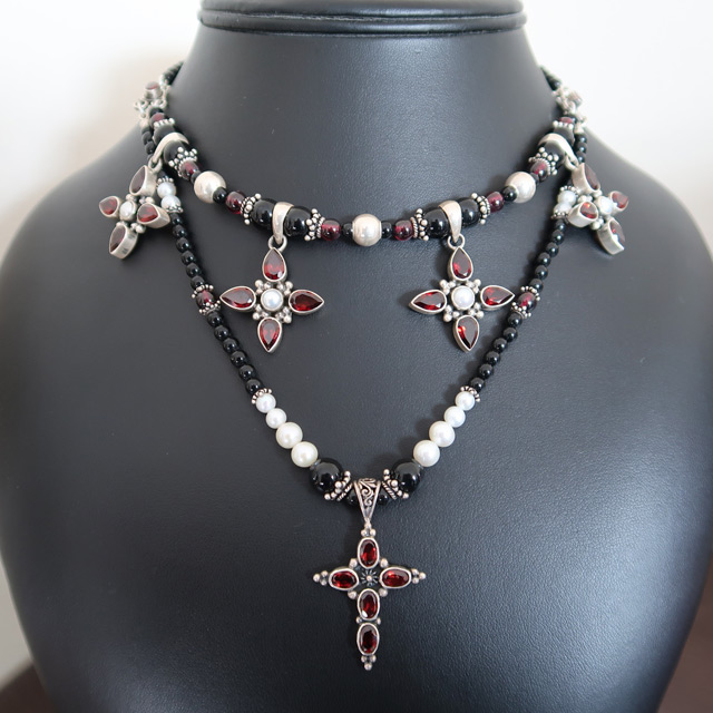 A white glass pearl and black onyx necklace with garnet cross pendants